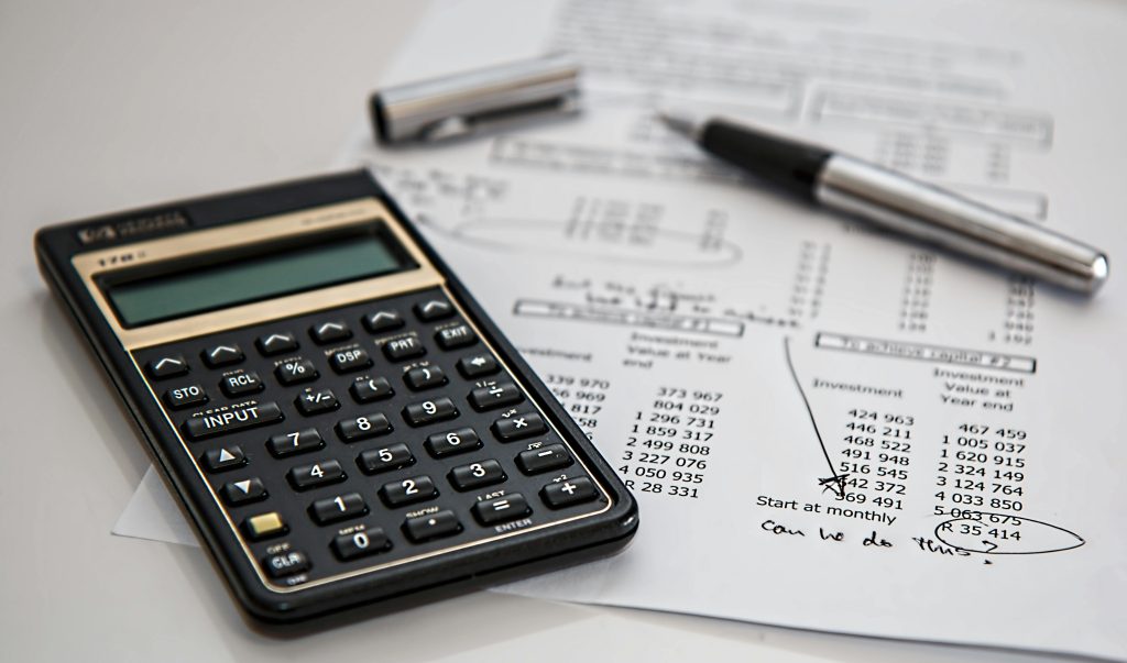 calculator,pen and paper is on a white table